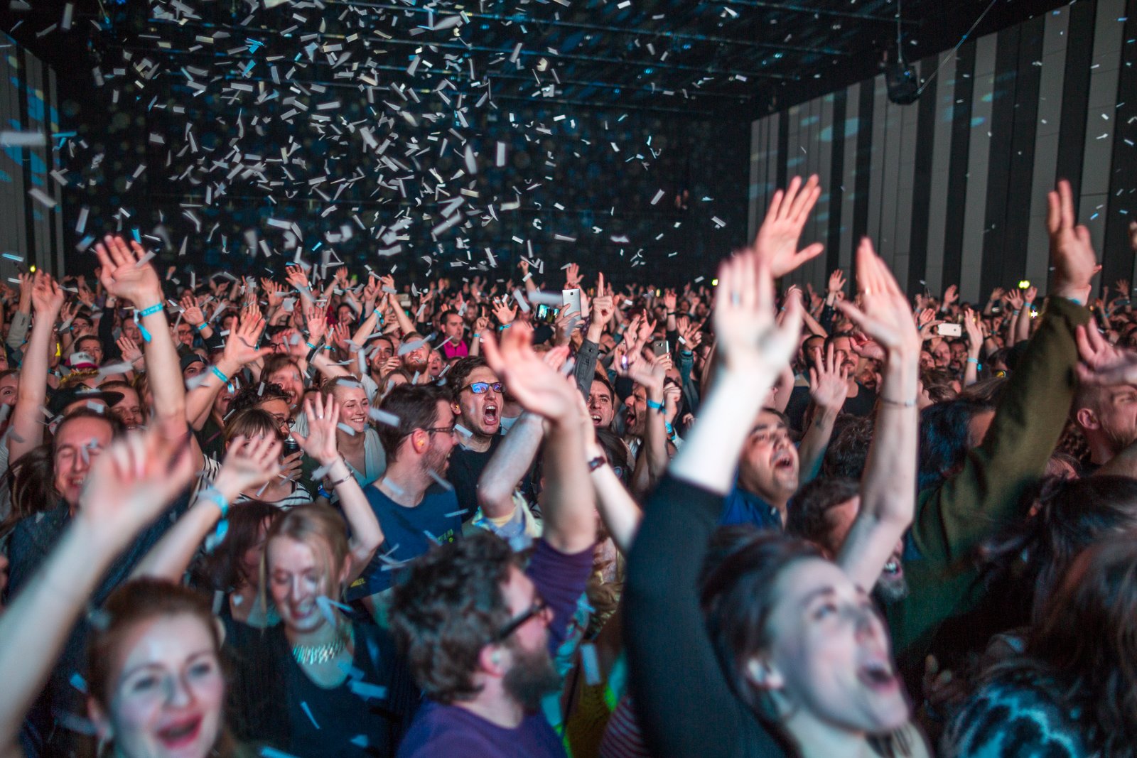 A crowd screams as confetti falls from the ceiling 